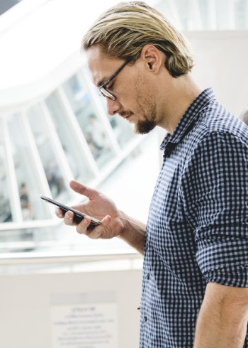 Man in Black and Gray Tattersall Dress Shirt Holding Smartphone