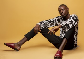 Man in Black and White Long-sleeved Shirt and Black Bottoms With Red Slide Sandals Sitting Down 