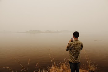 Man in Black and White Plaid Dress Shirt Standing Near Body of Water