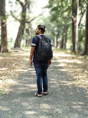 Man in Black and White T-shirt and Blue Denim Jeans Carrying Backpack