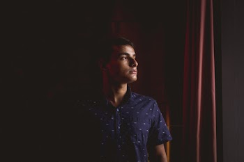 Man in Black Button-up Shirt Standing Beside Red Curtain