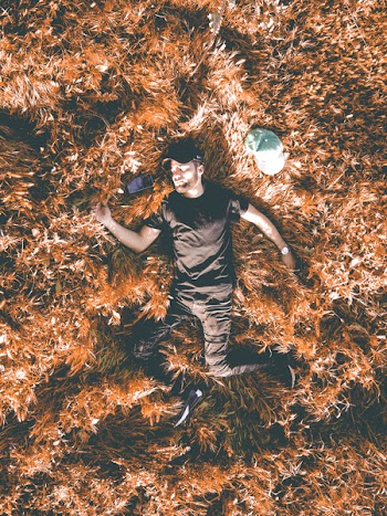 Man in Black Crew-neck Shirt and Black Pants Laying in Brown Dry Leaf