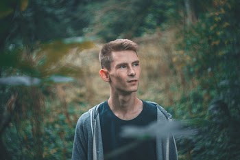 Man in Black Crew-neck Shirt Standing Near Green Leaf Plants