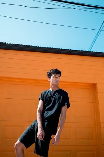 man in black crew-neck T-shirt and shorts standing in front of orange garage door