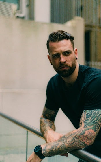 Man in Black Crew-neck Top Leaning on Metal Fence