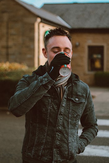 Man in Black Denim Jacket Drinking