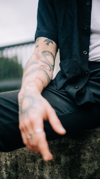 Man in Black Dress Shirt Sitting on Concrete Surface