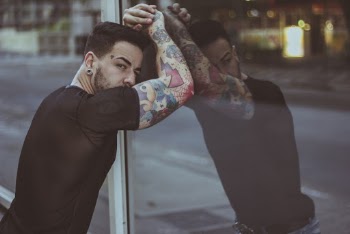 Man in Black Fitted Shirt Placing Arms on Glass Wall