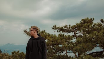 Man in Black Hoodie Standing Near Green Leaf Tree