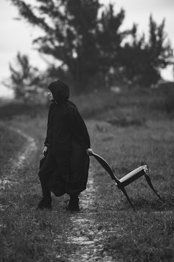 Man in Black Hoodie Walking on Grass Field