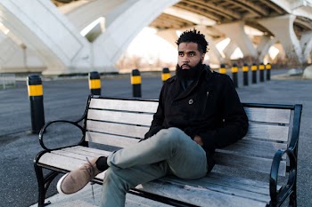 Man in Black Jacket Sitting on Outdoor Bench
