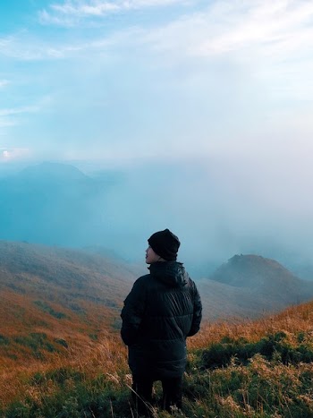 Man in Black Jacket Standing on Mountain With Fog