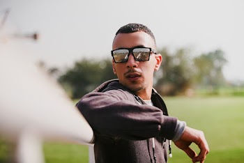 Man in Black Jacket Wearing Sunglasses Leaning on White Rails