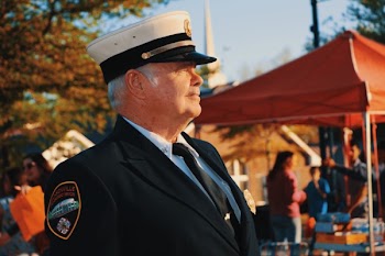 Man in Black Lapel Suit Jacket Wearing Police Cap Near Orange Canopy Tent