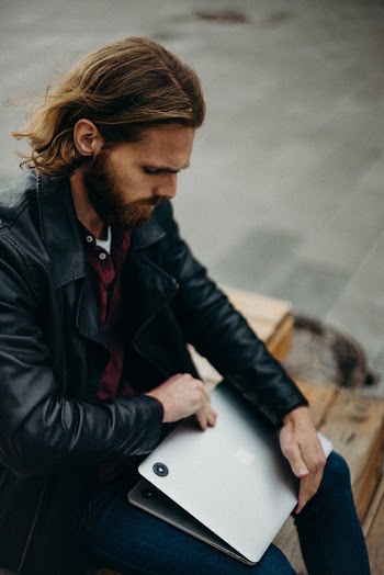 Man in Black Leather Jacket Holding Silver Macbook