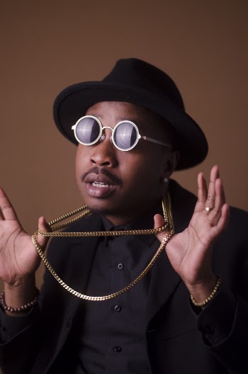 Man in Black Long-sleeved Shirt Wearing Black Sunglasses Holding Gold-colored Necklace