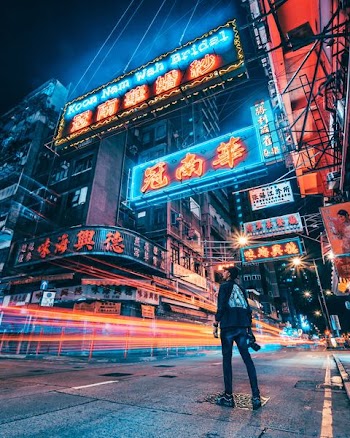 man in black pullover jacket standing while looking at assorted kanji text light signages