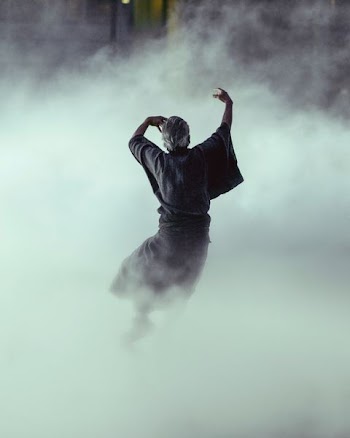 man in black robe surrounded by smoke inside room