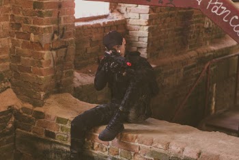 Man In Black Safety Gears Holding And Pointing Airsoft Gun