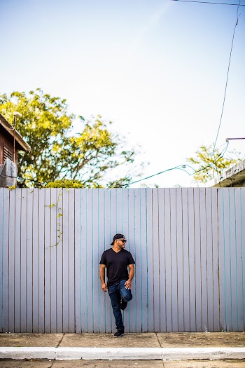 Man in Black Shirt and Blue Jeans Leaning on A White Painted Wall