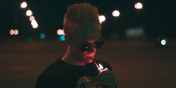 Man in Black Shirt Lighting Up Cigarette Stick during Nighttime