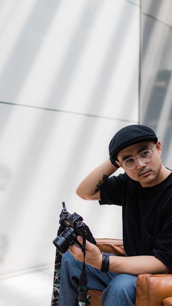 Man in Black Shirt Sitting on Brown Sofa With Dslr Camera