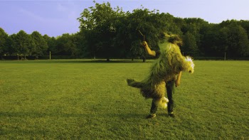 Man in Black Shirt Standing on Green Lawn While Playing With Brown Long Coat Medium Sized Dog