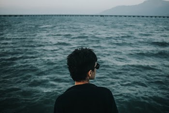 Man in Black Shirt Wearing Sunglasses Facing Body of Water