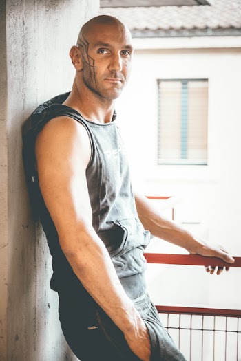 Man in Black Sleeveless Hoodie Leaning on Gray