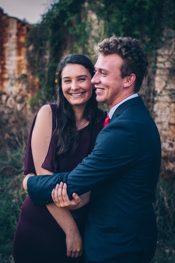 Man In Black Suit Hugging Woman In Maroon Dress