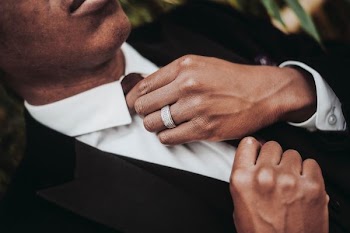 man in black suit jacket fixing his neck tie
