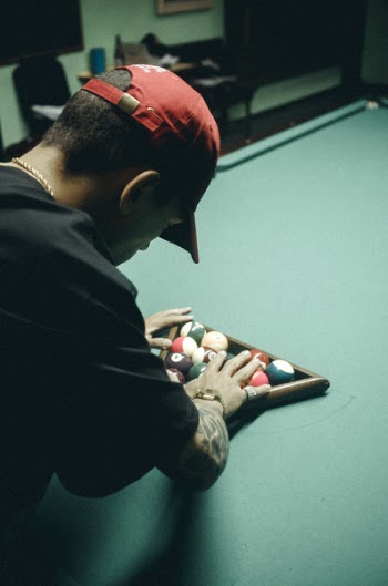 Man in Black T-shirt and Red Baseball Cap Arranging Billiard Balls on Table