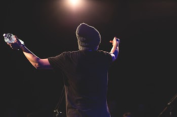 Man in Black T Shirt Standing While Spreading His Arms Facing Light