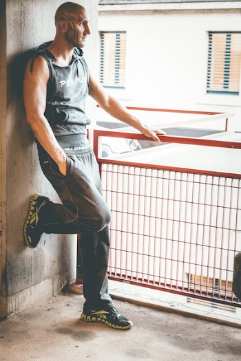 Man in Black Tank Top Leaning on Wall