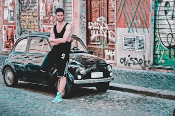 Man in Black Tank Top Standing Beside Black 3-door Hatchback