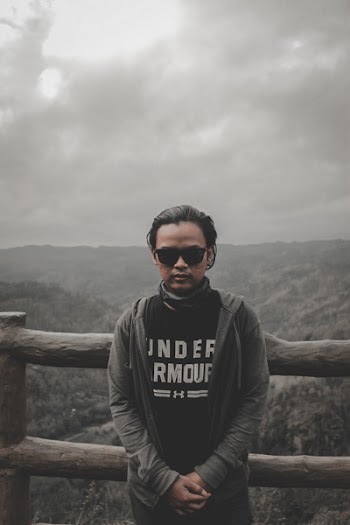 Man in Black Top and Grey Hoodie Jacket Standing Beside Brown Wooden