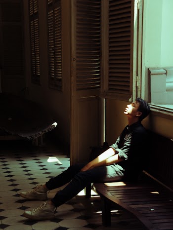 Man in Black Top Sitting on Bench Beside of Door