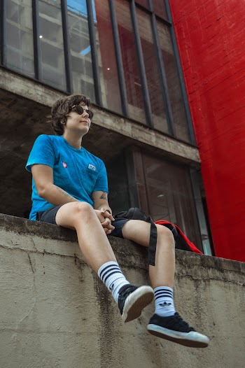 Man in Blue Crew-neck T-shirt Sitting on Grey Concrete Pavement