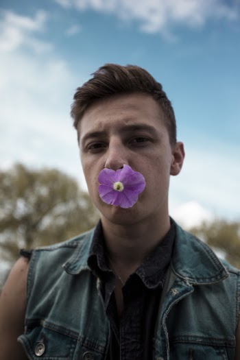 Man in Blue Denim Collared Vest With Purple Flower on Mouth