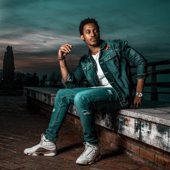 Man in Blue Denim Jacket and Jeans Sitting on Concrete Slab