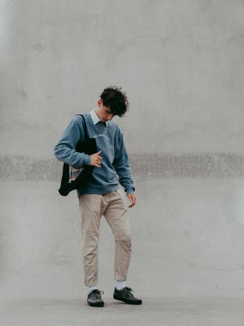 Man in Blue Dress Shirt and Brown Pants Standing Beside White Wall · Free Stock Photo