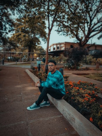 Man In Blue Long Sleeve Shirt Sitting Near The Flowers