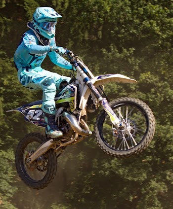 Man in Blue Mtx Suit Riding Blue and Yellow Dirt Motorcycle in Air
