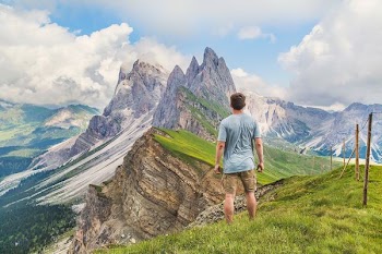 man in blue T-shirt on top of the mountain under the blue sky