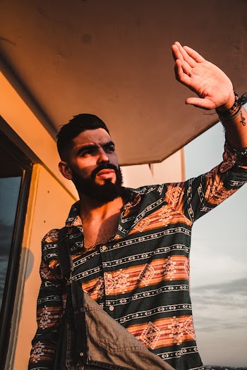 Man in Brown, Black, and White Tribal Print Dress Shirt Standing Beside Wall