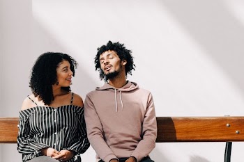 man in brown drawstring pullover hoodie sitting on brown bench beside woman