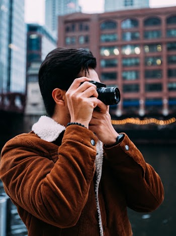 Man in Brown Jacket Holding Black Dslr Camera