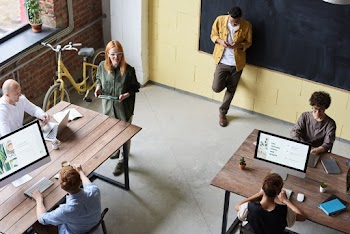 Man in Brown Jacket Leaning on Black Board