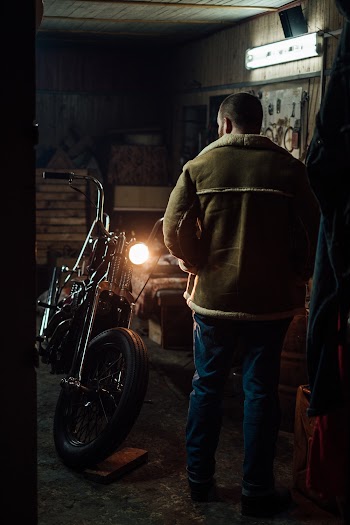 Man in Brown Jacket Looking At His Motorbike