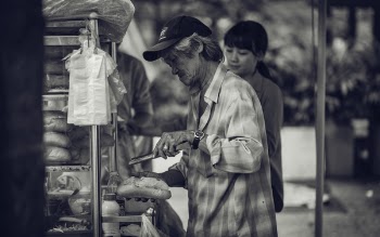 Man in Cap Holding a Pastry and Tong